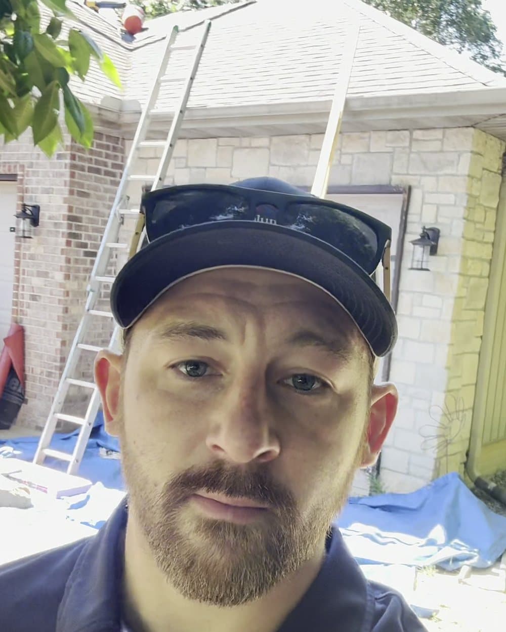 Dylan Sobczak, owner of Sobczak Exteriors, on a St. Louis job site with shingle bundles and a ladder behind him