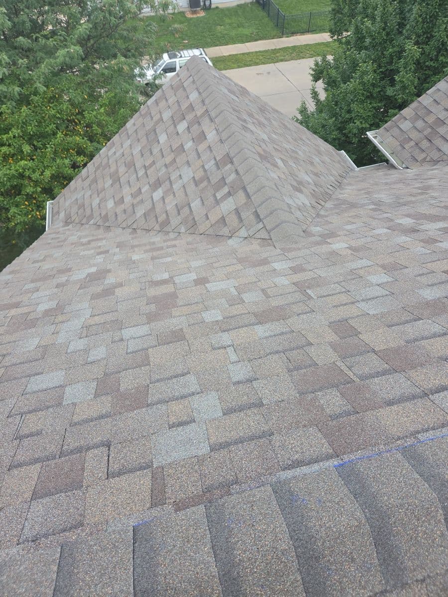 Finished driftwood-blend shingle roof with a clean hip and capped ridge
