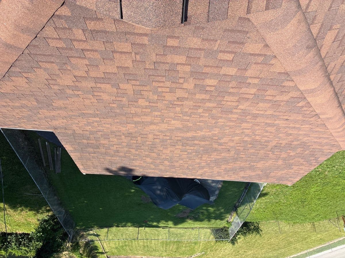 Overhead view of a terracotta-blend shingle roof, fenced back yard below